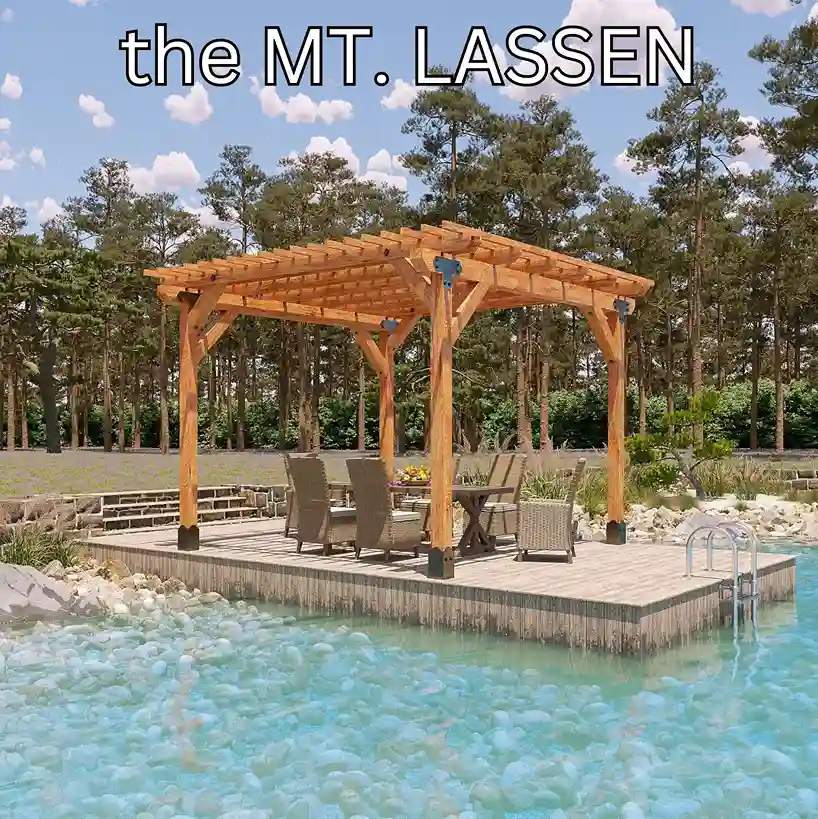 A four-post cedar pergola on a timber deck at the edge of a clear swimming pond, sheltering a dining table and chairs, with pines behind.