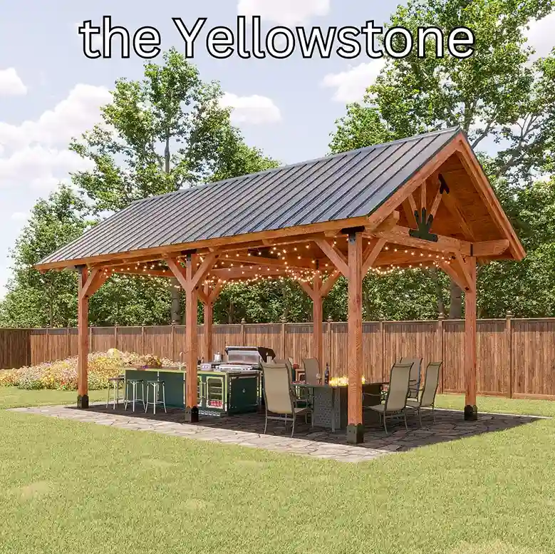 A large six-post cedar pavilion with a dark standing seam gable roof and exposed trusses, over an outdoor kitchen and dining table strung with lights.