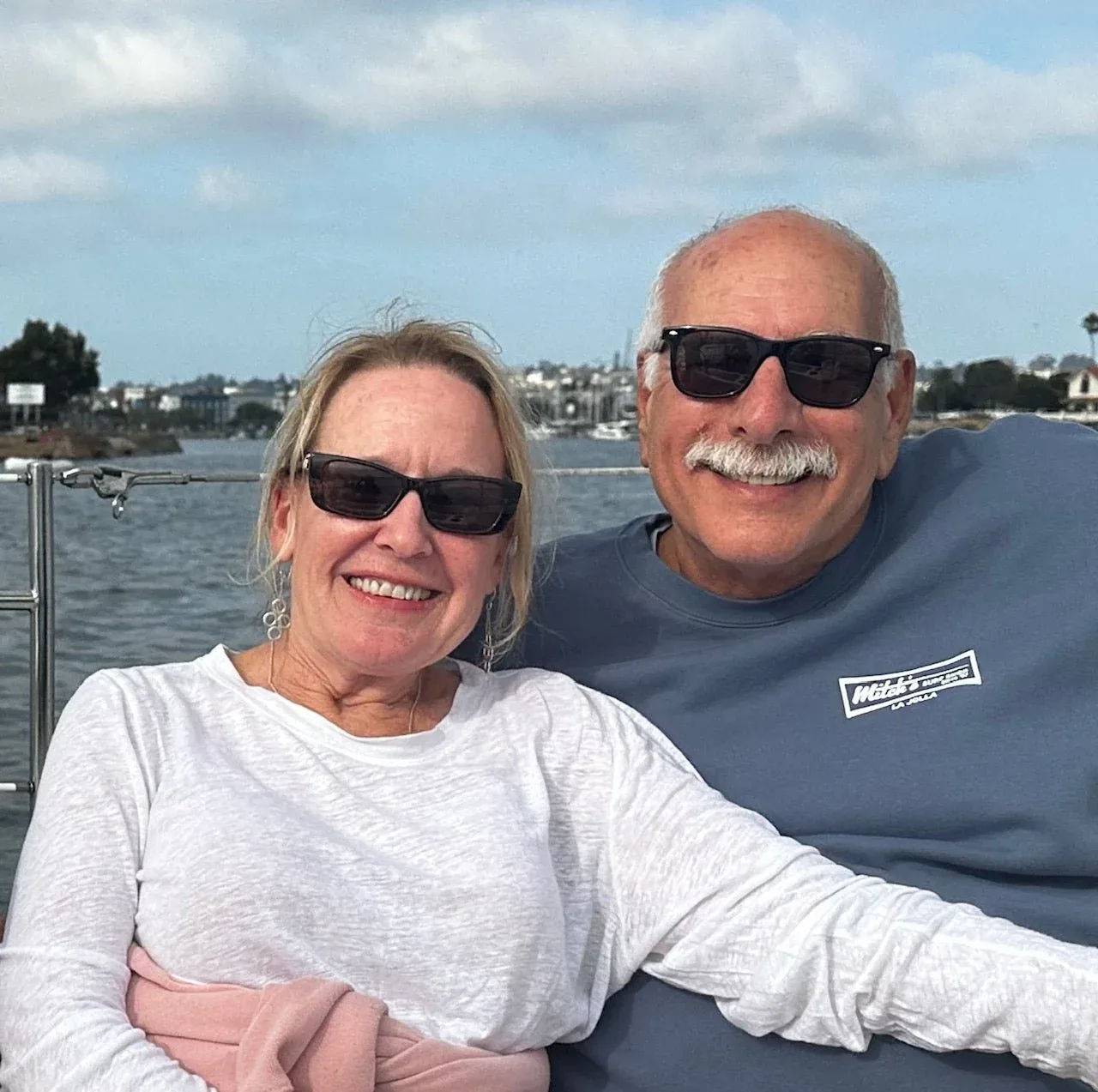 Larry and Sheri Trimboli, smiling in sunglasses by the water.
