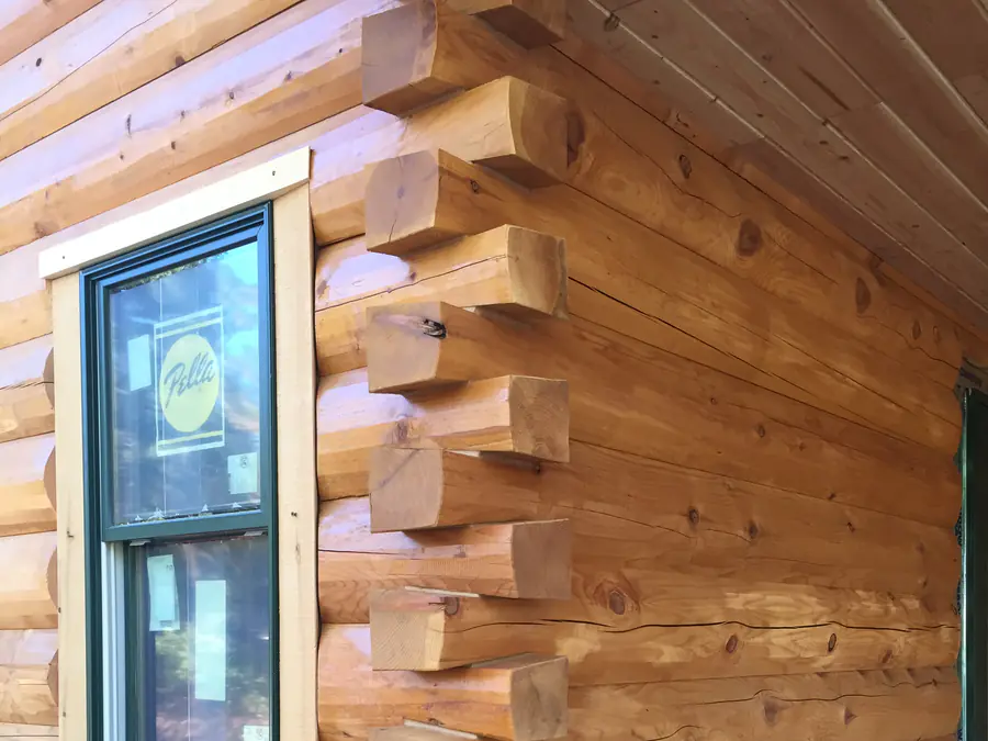 A D-log corner beside a window: rounded log faces outside, the ends squared and stacked at the corner.