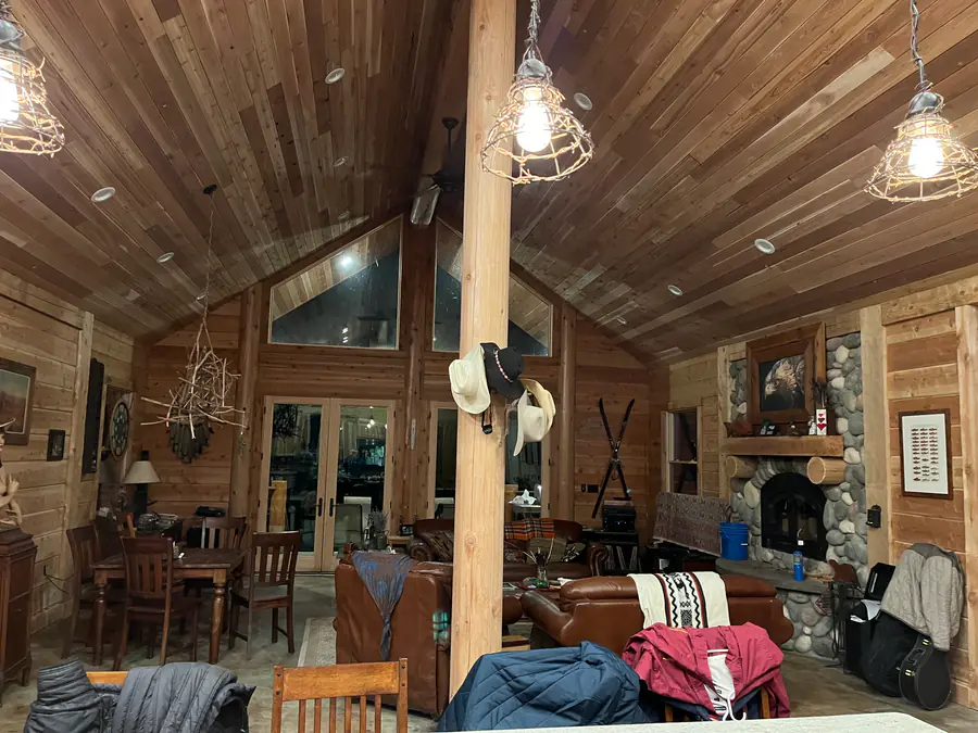 Inside a D-log home: the flat, hewn inner face of the log walls, a round log post and a vaulted wood ceiling.