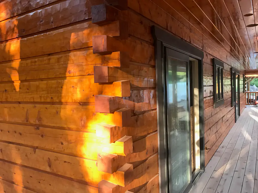 A dovetail corner up close: squared timbers interlocking at the corner of a hewn log wall, in low sun.
