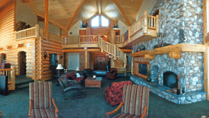 interior of lodge-style home with large stone fireplace and loft