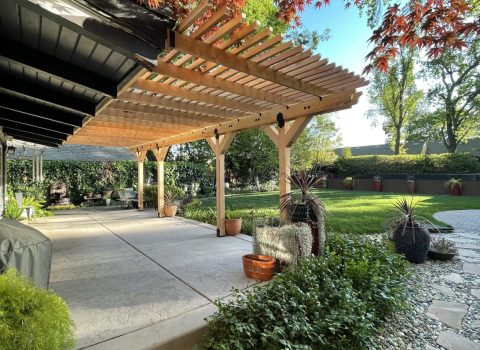A custom shade structure outdoors over a patio designed by Sierra Log & Timber